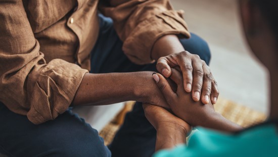 Mental health care provider holding the hands of a patient.